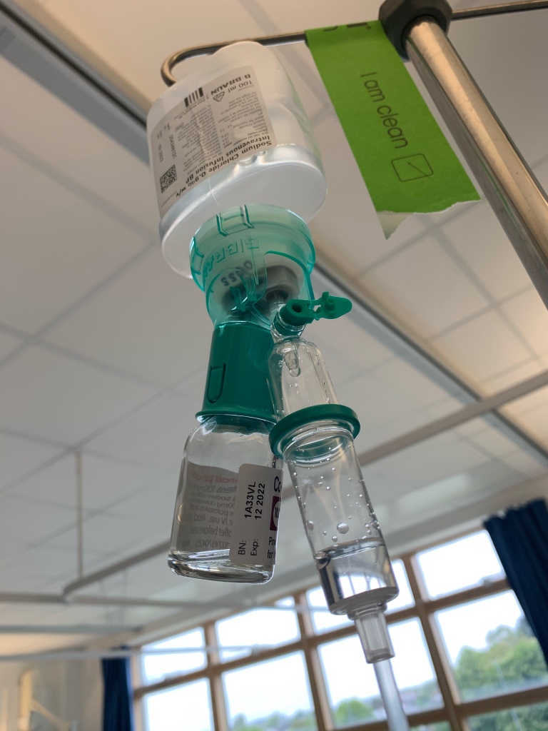 An empty bottle of intravenous antibiotics attached to a bottle of intravenous fluids for a patient during fluid therapy