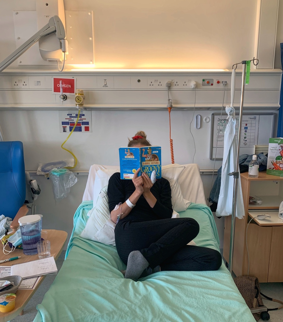 A hospitalised in-patient reading a childrens book on her bed on a ward